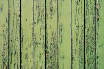 Old wooden painted rustic wall with green flaky dye. Faded wood planks close-up. Peeling paint on boards. Texture of damaged rough wooden of panels. Imperfect background. Weathered paint on old fence.
