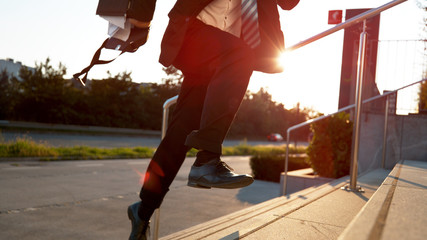 CLOSE UP: Man running late for work and scattering paperwork on sunny morning.