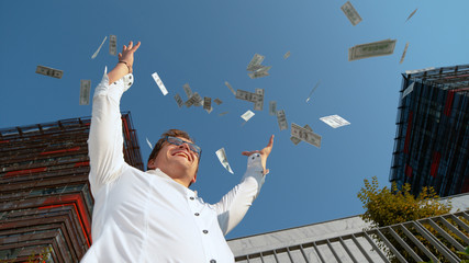 CLOSE UP: Smiling man celebrating winning the lottery by tossing money in air