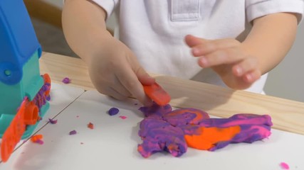 A two years old preschool child playing with modeling clay (compound). Smiling and looking at the camera. Early childhood education to children concept
