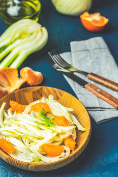 Fennel and orange citrus salad on wooden plate between ingredients