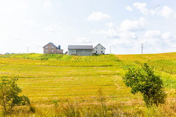 Landscape of farm fields hills and yellow grass green lawn with house in summer in Rivne oblast in Ukraine countryside during day