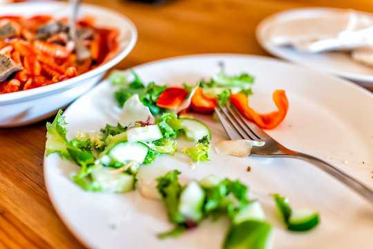 Closeup Of Wooden Table With Messy Half Eaten Green Vegetable Salad And Plate Fork Background