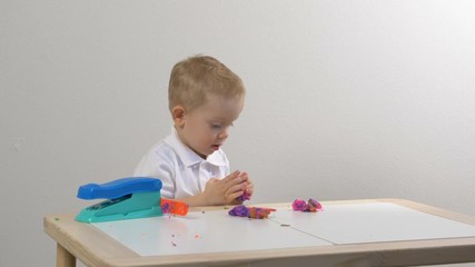 A two years old preschool child playing with modeling clay (compound). Smiling and looking at the camera. Early childhood education to children concept