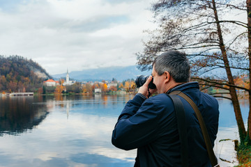 Man taking photos of Bled Lake and Church in Slovenia