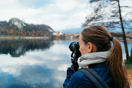 Lady taking photos of Bled Lake and Church in Slovenia