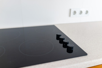 Closeup and knobs on modern luxury electric cook stove top stovetop cooktop with glass reflection...