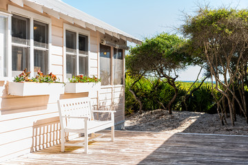 Wooden bench and cottage home house architecture in Florida beach by sand dunes during sunny day peaceful tranquil vacation