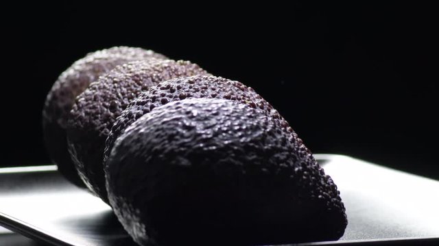 Hass avocados fruit gyrating on black background