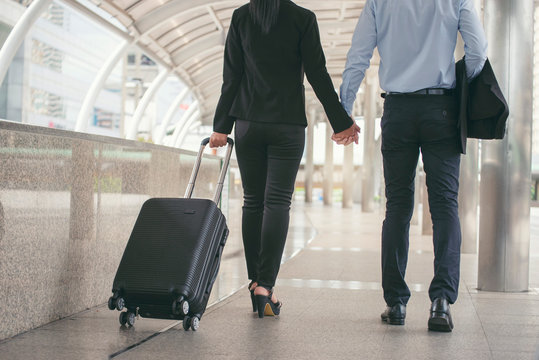 Business man and woman Dragging suitcase luggage bag,walking to passenger boarding in Airport,travel to work.Asian tourist men and women wearing black suit pull trolley bag. Business travel concept