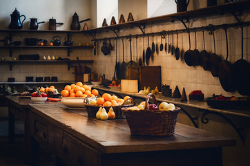 antique XIX century old kitchen with tools, pans, pots and food ingredients all over che benches and tables