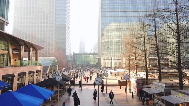 Motion lapse of Business Men and women at Canary Wharf durning morning rush hour, with large analog clocks spinning fast, Time and business concept.