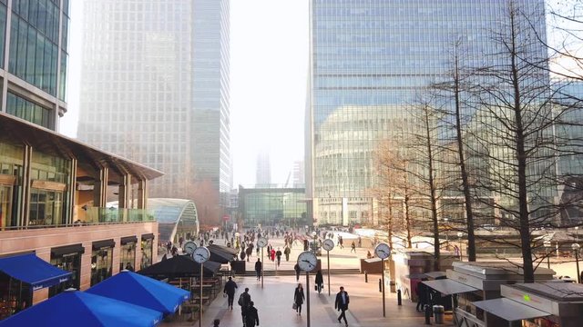 Motion lapse of Business Men and women at Canary Wharf durning morning rush hour, with large analog clocks spinning fast, Time and business concept.