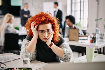 Young businesswoman feeling depressed while sitting at desk in the office.