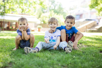 Naklejka na ściany i meble Three happy young boys in summer park