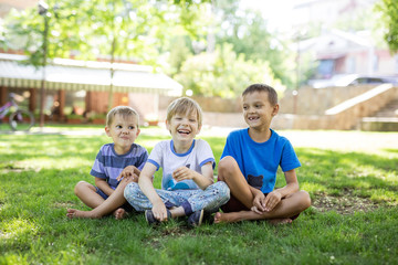 Three happy young boys in summer park