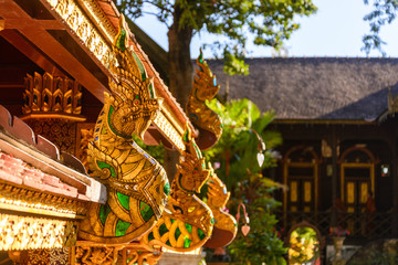 Obraz premium Asian ornament decorated detail of cornice with golden head of Naga, creature in Buddhist fairy tale, under the roof of temple in Thailand. 