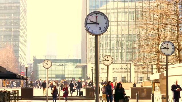 Time lapse of Business Men and women at Canary Wharf durning morning rush hour, with large analog clocks spinning fast, Time and business concept.