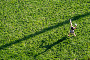 A woman does a hand stand in a park