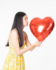 Asian young woman in yellow dress hold  red balloon heart. Young woman holding it with  being excited and surprised  holiday present isolated white  background.concept love surprise valentine day.