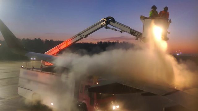 Aircraft De-Icing by Airport Ground Crew in De-Icing Truck at Dawn