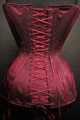 Closeup of red vintage female corset on grey studio background