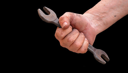 Close up of old mechanic's hand holding wrench, isolated on black