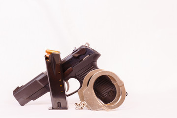 Pistol, clip and handcuffs with a white background