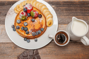 Healthy breakfast, coffee and homemade pancakes with fresh berries and banana