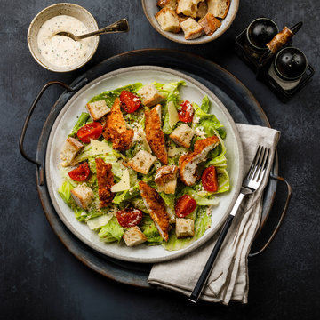 Caesar salad with Chicken breast meat on metal tray on dark background