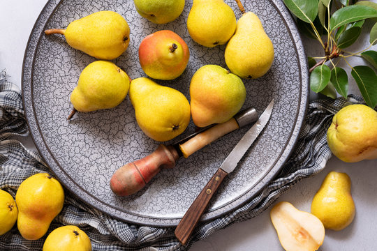 Ripe William pears on a plate with a knife and an apple corer.