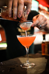 A bartender mixes a sweet delicious cocktail in a bar