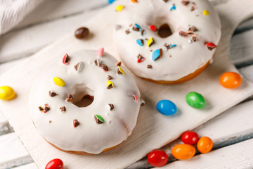 Cookery, baking and food concept - closeup. Donuts in white glaze with color dragee on a decorative...