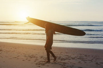 Silhouette of Male surfer with long board on the sea sunset