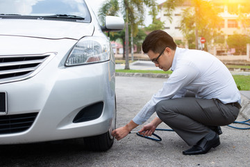 asian man pumping air to his car tyre