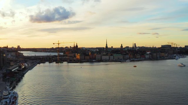 Aerial, rising, drone shot, towards the bridges to the old town island, the Gamla Stan of Stockholm city, at sunset, on a sunny, summer evening, in Sodermanland, Sweden