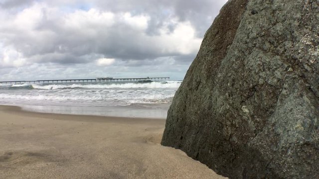 Shoreline beach scene, pier in the distance, smooth sand from fresh tide change early morning. Beach rock used for parallax. Mildly color graded, plenty of headroom for customizing.