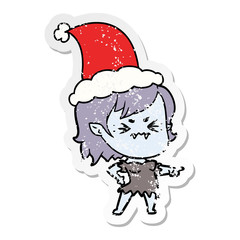 annoyed distressed sticker cartoon of a vampire girl wearing santa hat