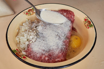 fresh beef and pork minced meat sprinkled with white onions and chicken egg and salt and pepper Sprinkle sugar with a spoon. for making cutlets and schnitzel in a yellow iron plate.