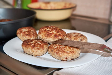 fried ready-made meat patties from pork beef and chicken on a white plate standing on a table on a white towel on top of a spatula for cooking homemade fresh hearty wholesome food. food at home.