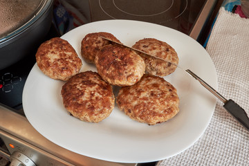 fried cooked meat patties from pork beef and chicken on a white plate standing on a table on a white towel on top of a spatula for cooking. homemade food. prepares food at home.