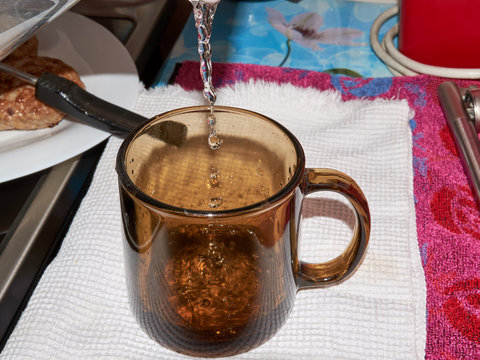 Closeup on housewife pouring water into glass from water filter pitcher