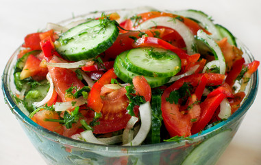 Healthy fitness salad with tomato, cucumber, onion, pepper, dill, parsley, olive oil, spice. Selective focus.