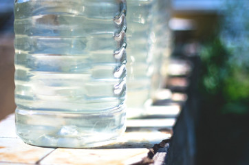 Row of Plastic Bottles Filled with Clean Water From a Public Well on a Bright Sunny Day. Water Supply Shortage, Climate Change Concept.