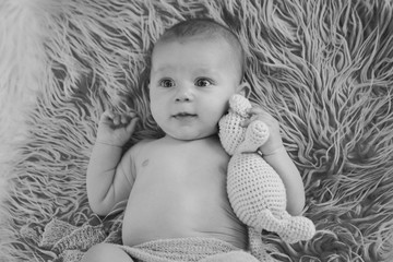 newborn baby sleeping with a toy next to the knitted teddy bear