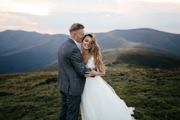 Beautiful wedding couple, bride and groom, in love on the background of mountains