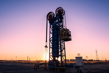 Oil pumps are running in the sunset at the oil field.