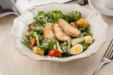 Healthy Grilled Chicken Caesar Salad with parmesan Cheese and Croutons on wooden table