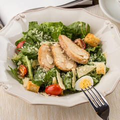 Healthy Grilled Chicken Caesar Salad with parmesan Cheese and Croutons on wooden table