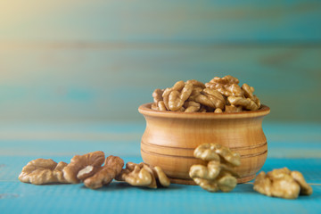 Walnuts on blue rustic table in wooden bowl